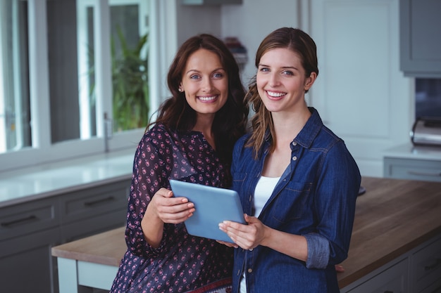 Duas mulheres bonitas usando tablet digital na cozinha