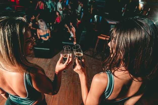 Foto duas mulheres brindando em uma festa noturna em uma boate