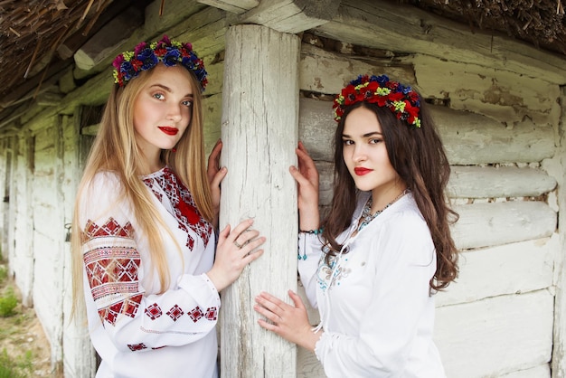 Duas mulheres com cabelo comprido em ucraniano em uma grinalda na aldeia étnica ucraniana ao ar livre