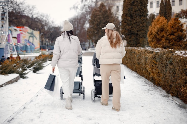 Duas mulheres com carrinhos de bebê andando na cidade juntos e conversando