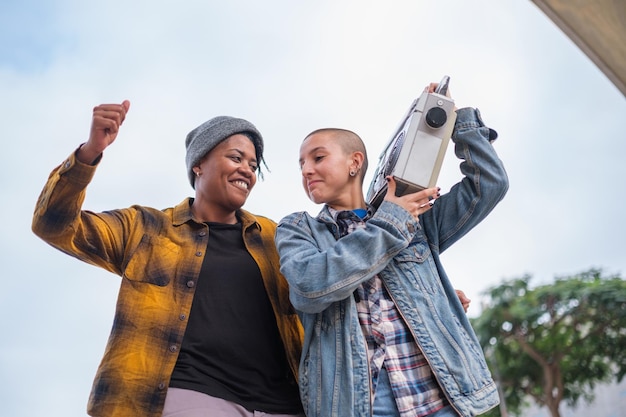 Duas mulheres com estilo urbano dançando ao ritmo do rádio vintage toca-fitas Concept Lifestyle feminismo estilo urbano