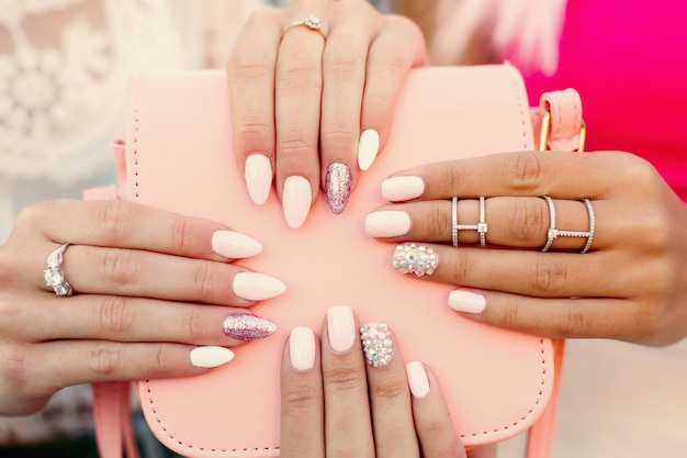 Duas mulheres com manicure de design segurando o saco de couro rosa.