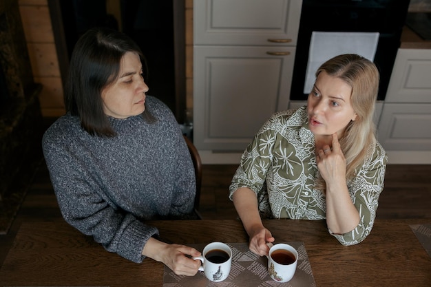 Duas mulheres conversando em casa Namoradas tomando café na cozinha