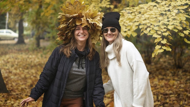 Duas mulheres de meia-idade, amigas, estão caminhando no parque de outono e rindo. Tonalidade marrom atmosférica, efeito cinema. Foco seletivo. O conceito de relacionamento entre mulheres