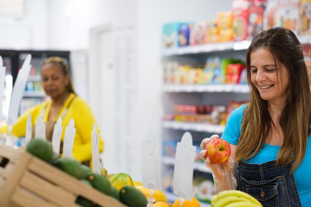 Duas mulheres de meia idade comprando frutas e legumes no mercado local