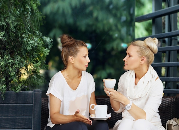 Duas mulheres de meia idade usando um smartphone e tablet ao ar livre