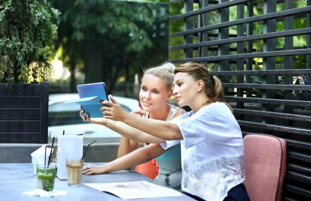 Duas mulheres de meia idade usando um smartphone e tablet ao ar livre
