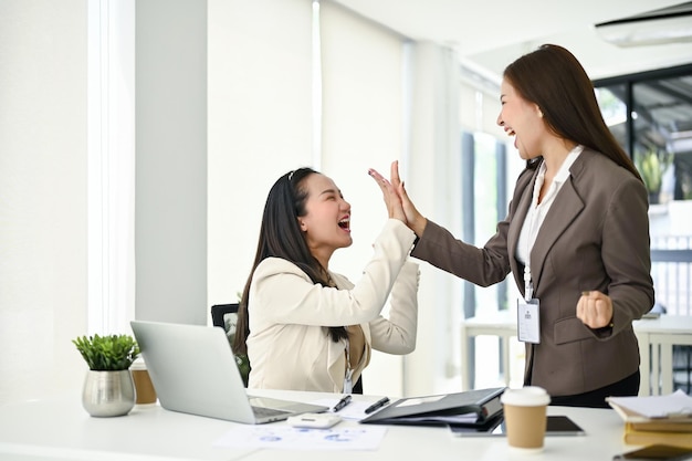 Duas mulheres de negócios alegres estão dando high fives para se animar