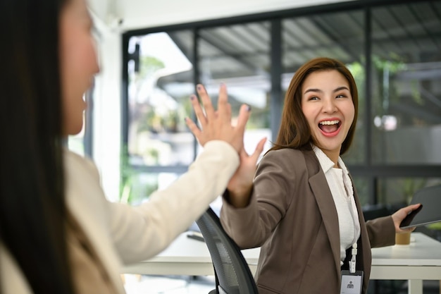 Duas mulheres de negócios animadas estão gritando de alegria e dando high fives para animar