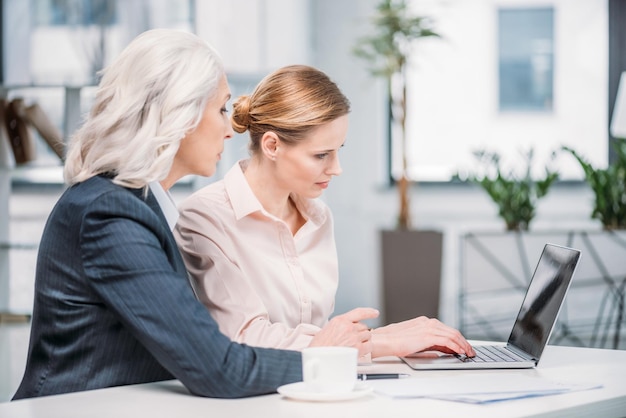 Duas mulheres de negócios com laptop discutindo projeto de negócios em reunião no escritório