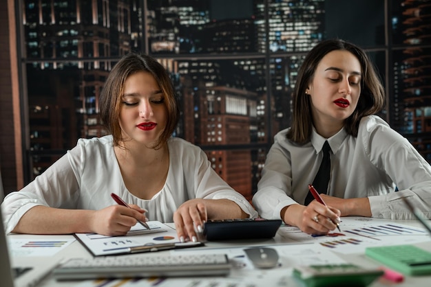 Duas mulheres de negócios jovens analisando documentos financeiros no escritório