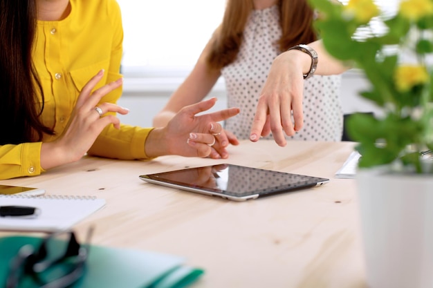 Duas mulheres de negócios ou amigos estão conversando e usando computador tablet.