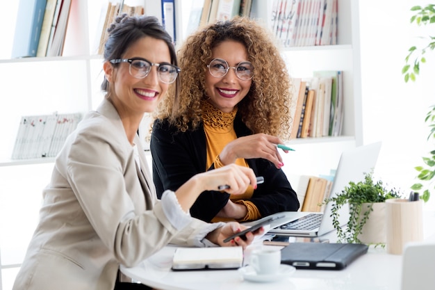 Foto duas mulheres de negócios que trabalham com laptop em seu escritório.