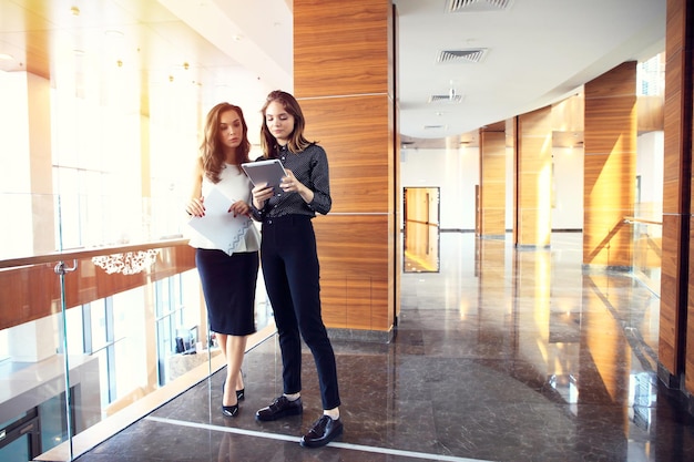 Duas mulheres de negócios tendo uma reunião informal num escritório moderno