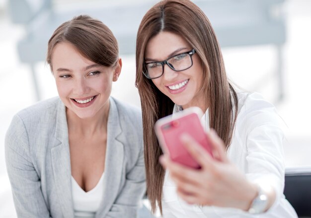 Duas mulheres de negócios tirando selfies na foto do escritório com espaço de cópia