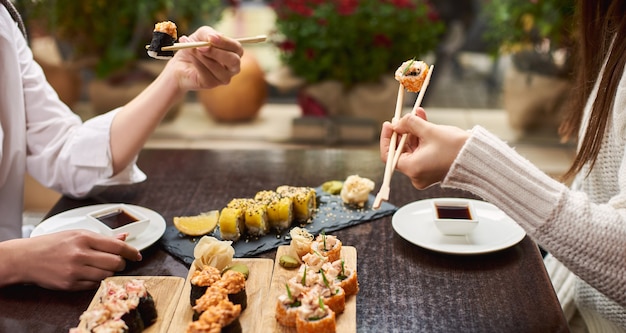Duas mulheres elegantes comendo sushi com wasabi e gengibre.