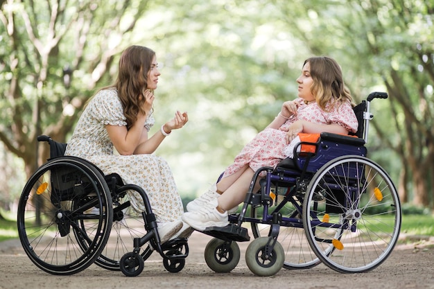 Duas mulheres em cadeiras de rodas conversando e sorrindo no parque