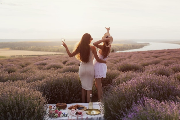 Duas mulheres em um campo de lavanda com um pôr do sol ao fundo