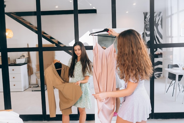 Duas mulheres escolhem e experimentam roupas em casa