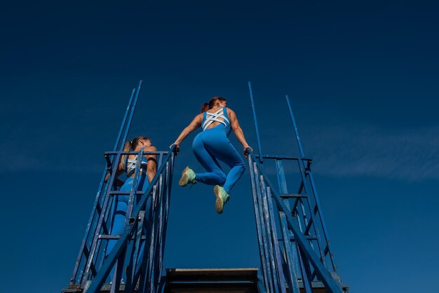 Duas mulheres estão pulando em uma escada, uma delas está vestida de azul.