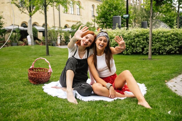 Duas mulheres fazendo piquenique juntos sentados na manta