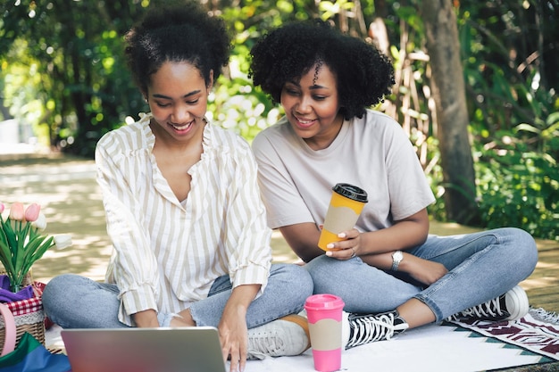 Duas mulheres felizes conversando e jogando laptop no jardim