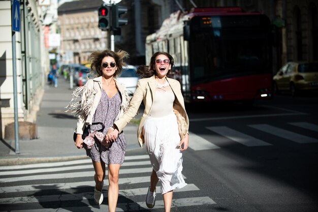 Duas mulheres felizes e animadas caminhando juntas na rua, férias engraçadas, viagem romântica