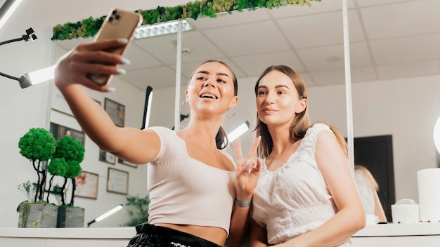 Duas mulheres felizes tirando uma selfie em um salão de beleza