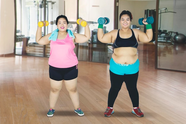 Duas mulheres gordas levantando halteres no centro esportivo