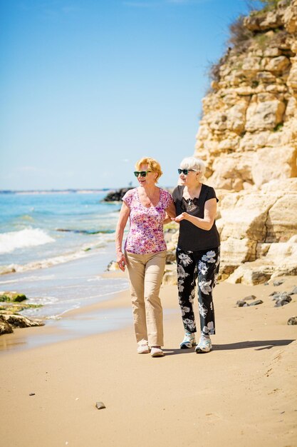 Duas mulheres idosas estão caminhando ao longo da costa rochosa