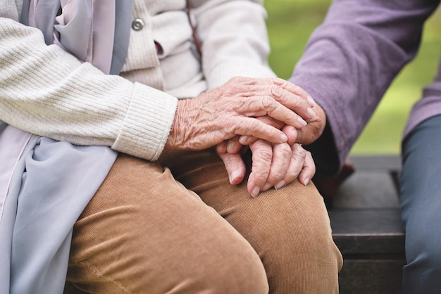 Duas mulheres idosas sentadas no banco no parque de mãos dadas felizes amigos de longa data aproveitando a aposentadoria