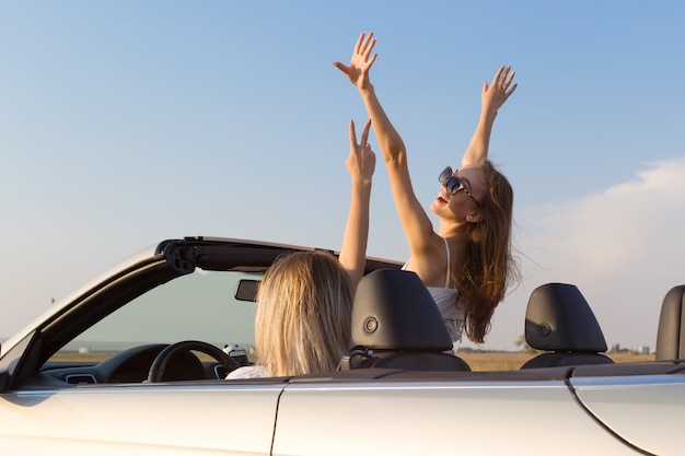 Duas mulheres jovens atraentes em um carro cabriolet