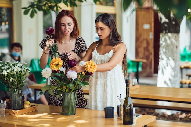 Duas mulheres jovens compõem um lindo buquê festivo