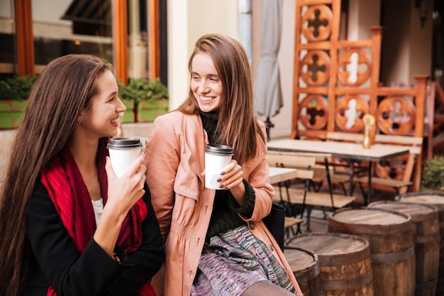 Duas mulheres jovens e alegres conversando e tomando café na cidade velha