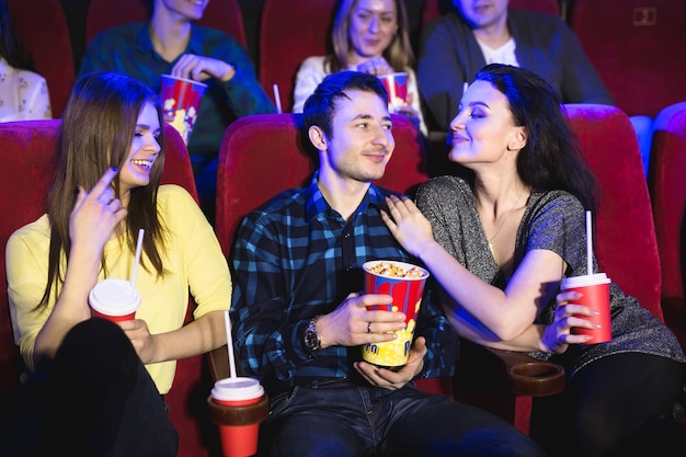 Duas mulheres jovens e um cara assistindo a uma comédia no cinema