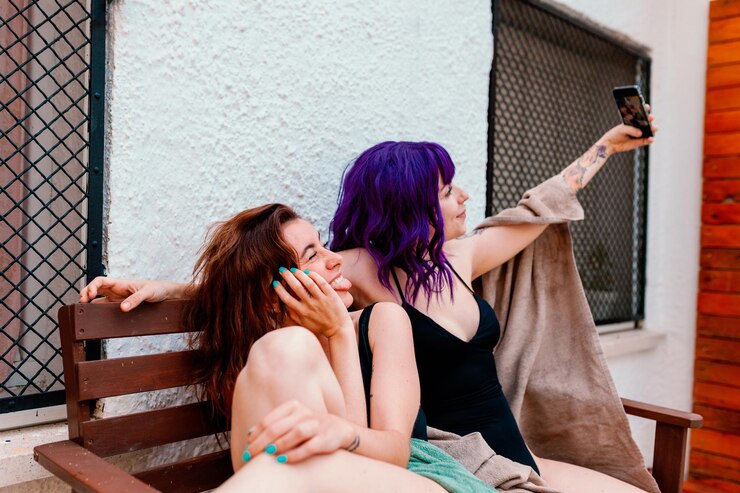 Foto duas mulheres jovens no quintal no verão tirando fotos com seus telefones celulares