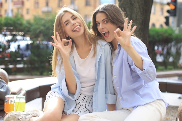 Foto duas mulheres jovens sorrindo hipster em roupas de verão, posando na rua. mulher mostrando emoções positivas do rosto.