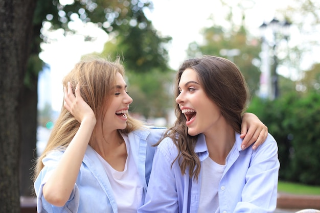 Duas mulheres jovens sorrindo hipster em roupas de verão, posando na rua. Mulher mostrando emoções positivas do rosto.