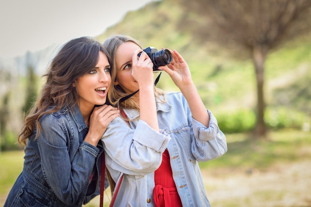 Duas mulheres jovens turistas tirando fotografias ao ar livre