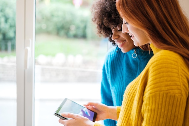 Duas mulheres jovens usando os novos aplicativos para controlar dispositivos em casa Conceito de tecnologia lgtbi estilo de vida