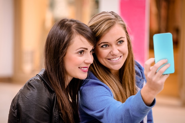 Foto duas mulheres lindas tomando uma selfie no shopping