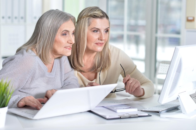 Duas mulheres maduras usando laptop e computador