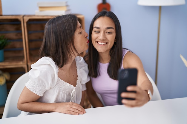 Duas mulheres mãe e filha fazem selfie por smartphone em casa