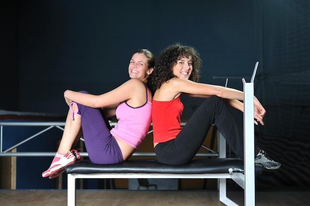 duas mulheres malham e alongam no clube de fitness