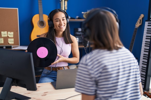 Foto duas mulheres músicos ouvindo música segurando disco de vinil no estúdio de música