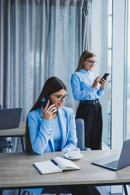 Duas mulheres no escritório estão trabalhando e fazendo negócios mulher de negócios no escritório com óculos e telefone gerente de mulher de óculos e camisa no escritório chefe do dia de trabalho