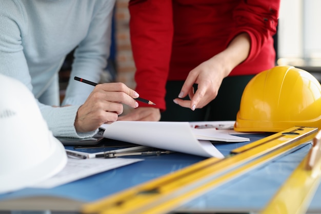 Duas mulheres olhando documentos e mostrando-os a lápis na coordenação do estúdio de design