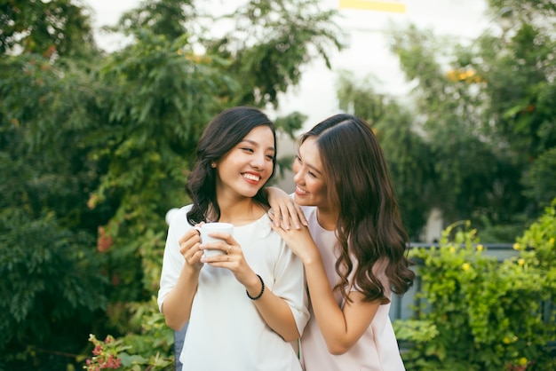 Duas mulheres relaxando no jardim da cobertura, bebendo café