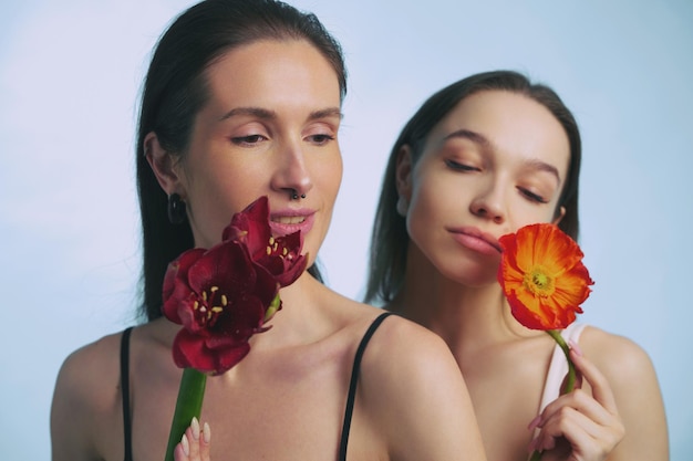 Duas mulheres segurando flores vibrantes em um ambiente de estúdio suavemente iluminado
