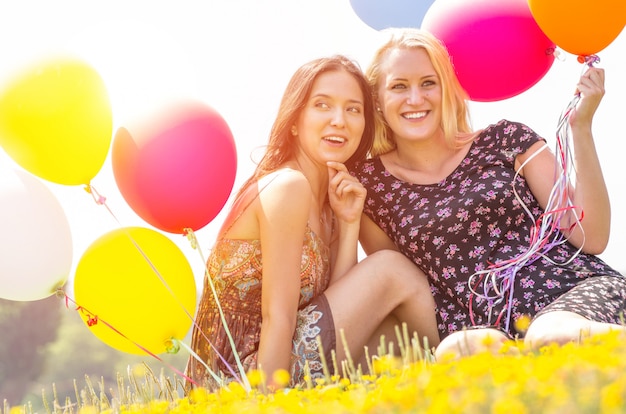 Duas mulheres sentadas em campo com balões